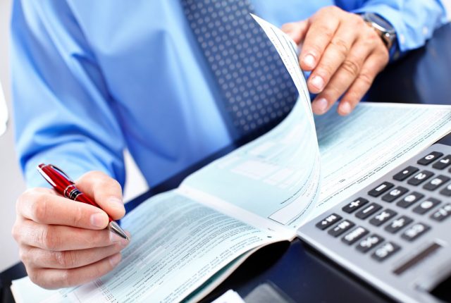 business professional reviewing financial documents with a calculator and pen